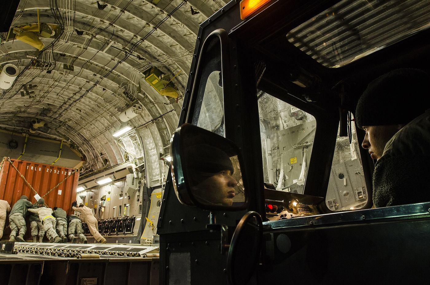 Pallets being loaded into a cargo aircraft on an apron at dusk.